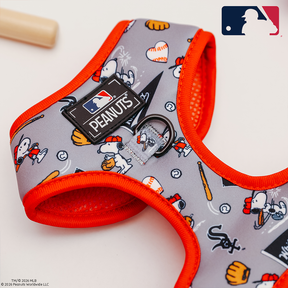 The Sassy Woof Dog Adjustable Harness - MLB™ x Peanuts™ Chicago White Sox™ features Snoopy and Woodstock playing baseball, a leash ring, and MLB and Peanuts logos, with a bat in the background and the MLB logo in the top right corner.