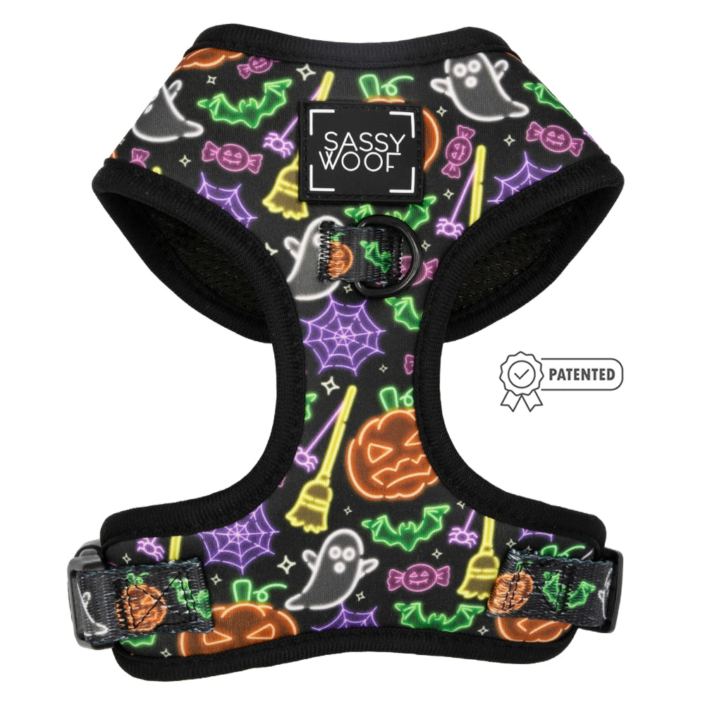 The Sassy Woof Dog Adjustable Harness – Neon Frights features neon Halloween designs with ghosts, pumpkins, and bats. It offers comfort, a patented icon, and a signature front label—perfect for your pup’s spooky festivities.
