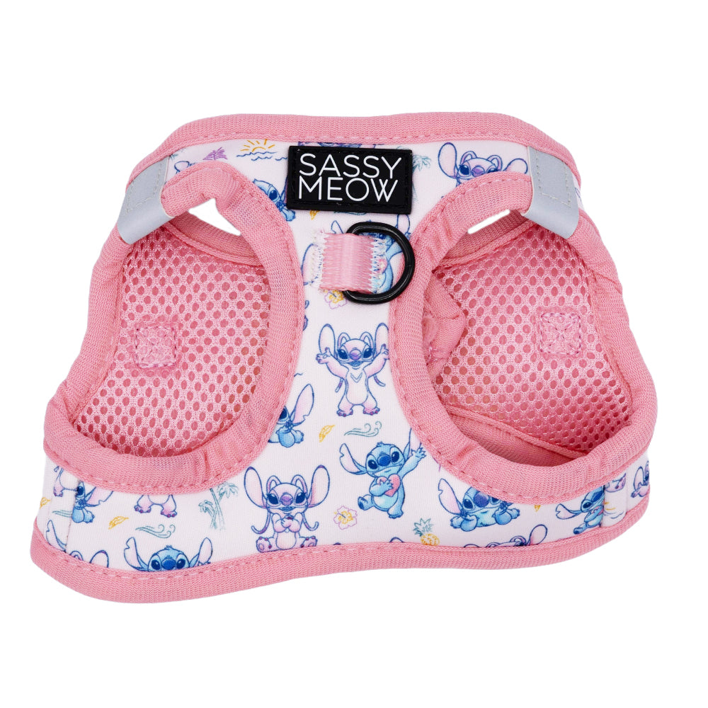 The Sassy Woof Cat Step-In Harness - Disney's Stitch Peach is a pink mesh harness with "Sassy Woof" label, blue cartoon Stitch prints, adjustable straps, a metal leash ring, and reflective strips for safer evening walks.