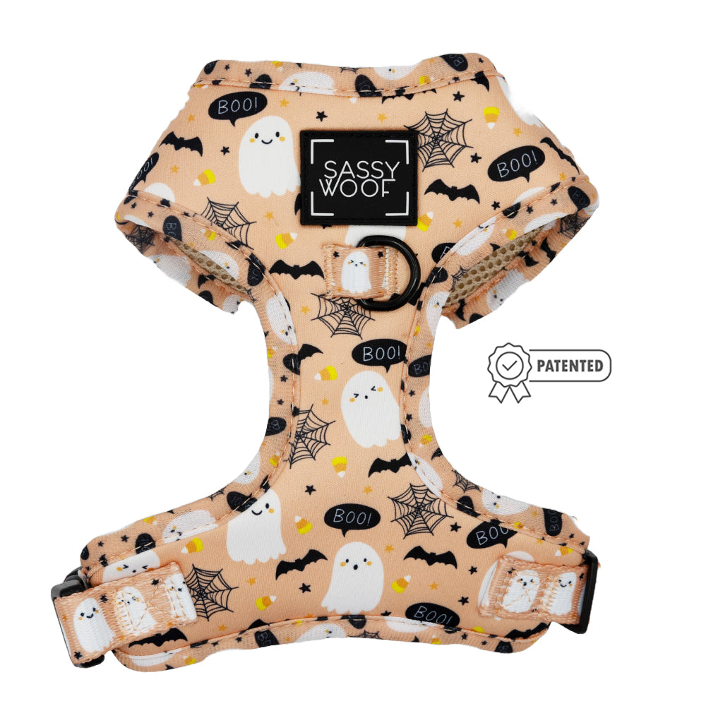 The Sassy Woof Dog Adjustable Harness - Squad Ghouls features a light tan design with cute ghost, bat, spiderweb, and candy corn prints, playful BOO! text in black and yellow, plus a Sassy Woof label and Patented badge on the front.
