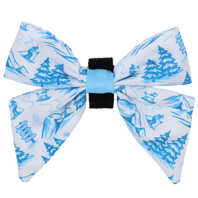 Introducing the Dog Sailor Bow - Après Ski Club by Sassy Woof—a white and blue sailor bow with a black center, adorned with a charming winter scene of trees, skiers, sleds, and snowflakes. Perfect for pairing with cozy dog collars or other winter accessories from the Après Ski Club collection.