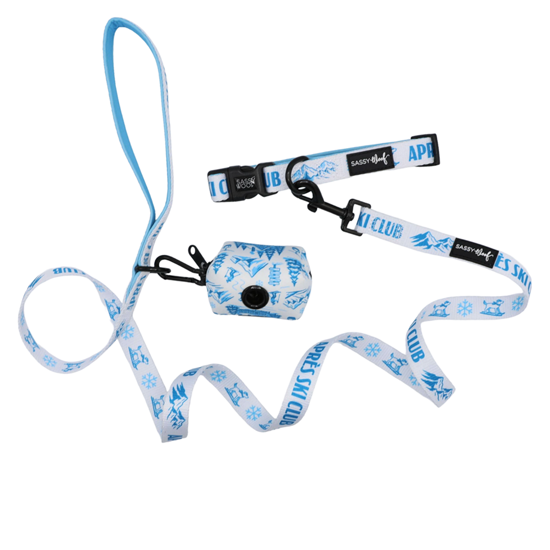 Introducing the Sassy Woof Dog Collar Three Piece Bundle - Après Ski Club: a blue and white leash set featuring a collar and a small attached pouch. The playful design showcases “SKI CLUB” lettering along with snowflake and mountain graphics, making it the perfect winter accessory for pups ready to join the Après Ski Club.