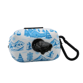 Introducing the Dog Waste Bag Holder - Après Ski Club by Sassy Woof: a compact neoprene pouch adorned with blue winter-inspired designs, featuring a front dispenser for black waste bags and a black carabiner clip on the right. This stylish accessory is perfect for adding après ski flair to your dog’s look during daily walks.