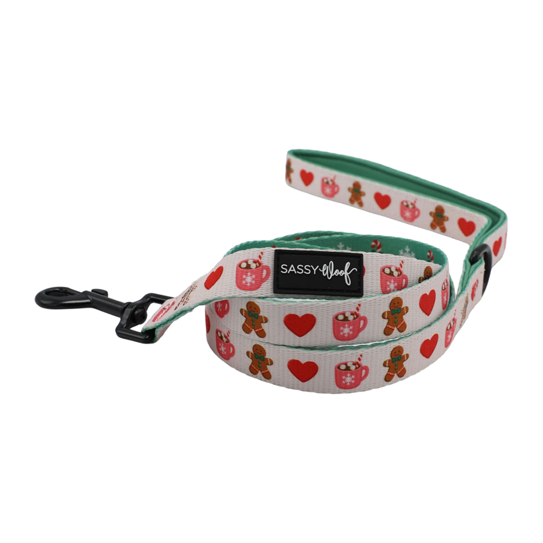 Bring holiday cheer to your pup with the Sassy Woof Dog Four Piece Bundle – Cocoa & Cookies. This festive set features charming gingerbread men, red hearts, and ornaments on a crisp white background. Complete with a sturdy black metal clasp and the signature Sassy Woof label, these accessories coordinate perfectly—mix and match with an adjustable harness for a stylish seasonal look.
