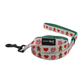 Bring holiday cheer to your pup with the Sassy Woof Dog Four Piece Bundle – Cocoa & Cookies. This festive set features charming gingerbread men, red hearts, and ornaments on a crisp white background. Complete with a sturdy black metal clasp and the signature Sassy Woof label, these accessories coordinate perfectly—mix and match with an adjustable harness for a stylish seasonal look.