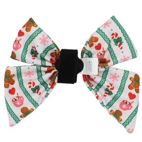 The Sassy Woof Dog Sailor Bow - Cocoa & Cookies features festive green and white stripes adorned with gingerbread men, candy canes, hearts, and snowflakes. This bow is accented with a black center and a small white tag—perfect for pairing with your favorite holiday-season pet accessories or an adjustable harness for a coordinated look.