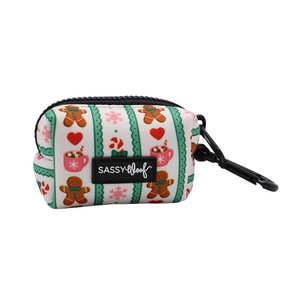 The Sassy Woof Dog Waste Bag Holder - Cocoa & Cookies features a small zippered pouch adorned with gingerbread cookies, mugs, hearts, snowflakes, and green stripes. It includes a black clip and showcases the signature Sassy Woof label. Part of the festive Cocoa & Cookies collection, this versatile accessory coordinates perfectly with your adjustable harness for stylish walks throughout the season.