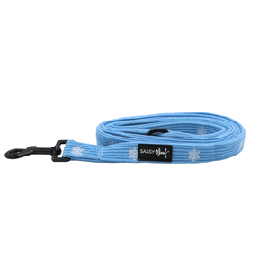 Sassy Woof Dog Leash - Morning Frost, a light blue coiled leash featuring a repeating white snowflake pattern, a padded neoprene handle, and a black metal swivel clip.