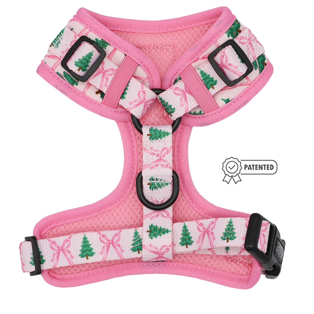 Bring festive flair to your pup’s winter wardrobe with the Sassy Woof Dog Adjustable Harness - Pretty in Pine. This pink harness features white straps adorned with green Christmas trees and pink bows, plus adjustable black buckles and rings for a secure, customizable fit. A patented label with a ribbon icon on the right adds an extra touch of style and assurance of quality—making this harness both fashionable and functional for your dog.