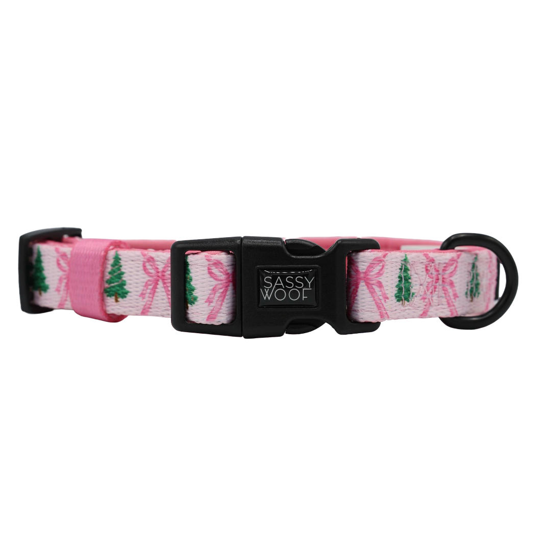 A Dog Collar Three Piece Bundle - Pretty in Pine by Sassy Woof, showcasing festive Christmas tree and bow designs in pink, features a black plastic buckle branded with “Sassy Woof” and a durable black metal ring—perfect for coupling with an evergreen dog leash and an essential addition to any winter dog accessory collection.