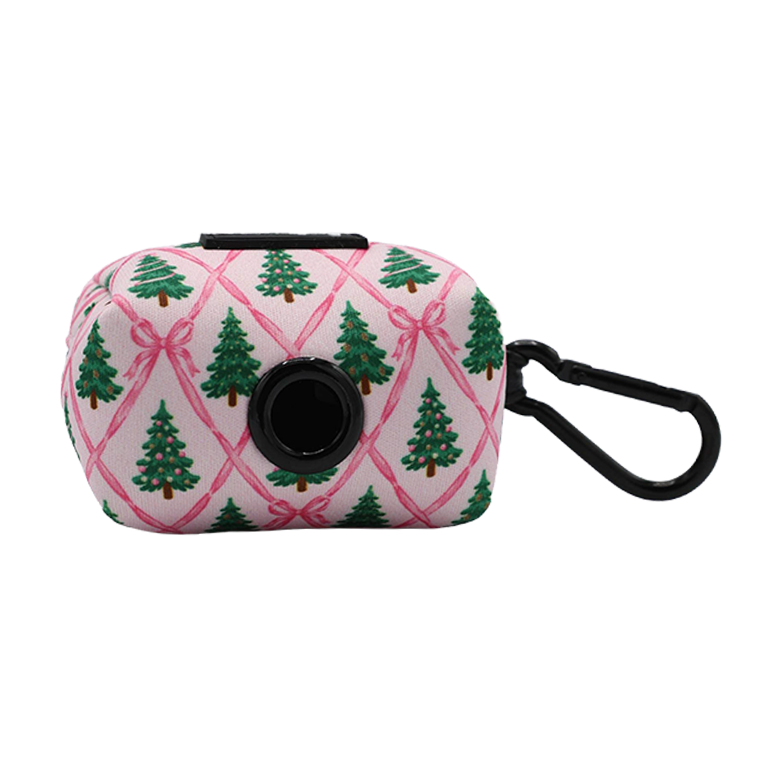 The Sassy Woof Dog Four Piece Bundle - Pretty in Pine includes a pink pouch adorned with green Christmas trees and pink bows, featuring a black circular dispenser and side clip—ideal for matching with your Pretty in Pine dog harness or other winter accessories.