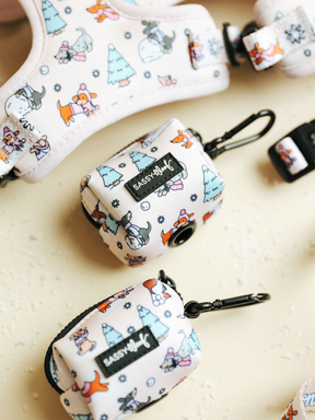 The Weenie Wonderland Collection by Sassy Woof features playful patterned dog accessories on a pale background, including the Dog Waste Bag Holder – Weenie Wonderland with convenient clips. Showcasing lively dog, fox, and tree illustrations, these pieces make perfect winter accessories for dachshunds.