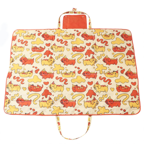 The Sassy Woof Dog Picnic Blanket - Hot Dawg features a yellow and orange cartoon cat pattern with playful cats, hearts, squiggles, orange trim, a handle, and an attached carrying pouch. It's part of the Yuna Bugs x Sassy Woof Dachshund collection.