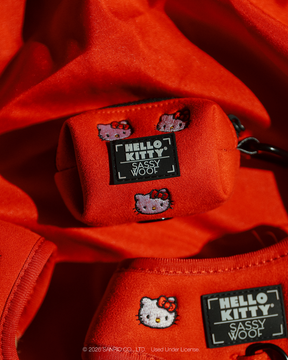 Red Sassy Woof Dog Waste Bag Holder - Hello Kitty® Chic, embroidered with Hello Kitty character faces and a branded rectangular label.