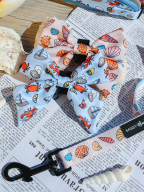 The Sassy Woof Dog Sailor Bow - Shell Yeah features double layers and a beach print with seashells, crabs, and sailboats—perfect for pairing with your dog's beachy collar or other seashell accessories.