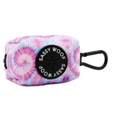 The Sassy Woof Dog Waste Bag Holder - Purple Haze is a small, rectangular pink and purple tie-dye neoprene bag with a black clip and Sassy Woof label—perfect for carrying waste bags in style with your matching harness set.