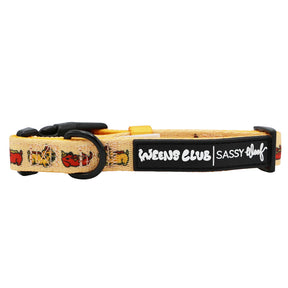 The Dog Collar - Hot Dawg by Sassy Woof is a yellow adjustable collar with cartoon dachshund designs, a black buckle and ring, and WEENS CLUB SASSY WOOF label—perfect for fans of the weenie-inspired collection.