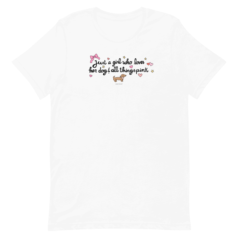 The Sassy Woof "Just A Girl Tee" features a white design with a pink bow, small dog, hearts, and stars. Printed with eco-friendly ink, it says: Just a girl who loves her dog & all things pink.