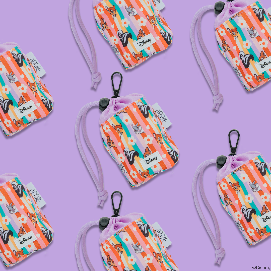 The Sassy Woof Treat Pouch - Disney's Bambi features orange and pink stripes, cartoon animal faces, a purple background, drawstring, and clip—making it the perfect cute dog accessory.