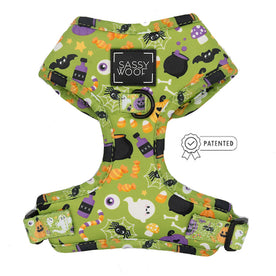 The Dog Adjustable Harness - Haunt Mess by Sassy Woof features a green no-pull design with a Halloween-themed pattern of candy corn, bats, spiders, potion bottles, eyeballs, and ghosts. Includes the Sassy Woof label with a patented symbol.