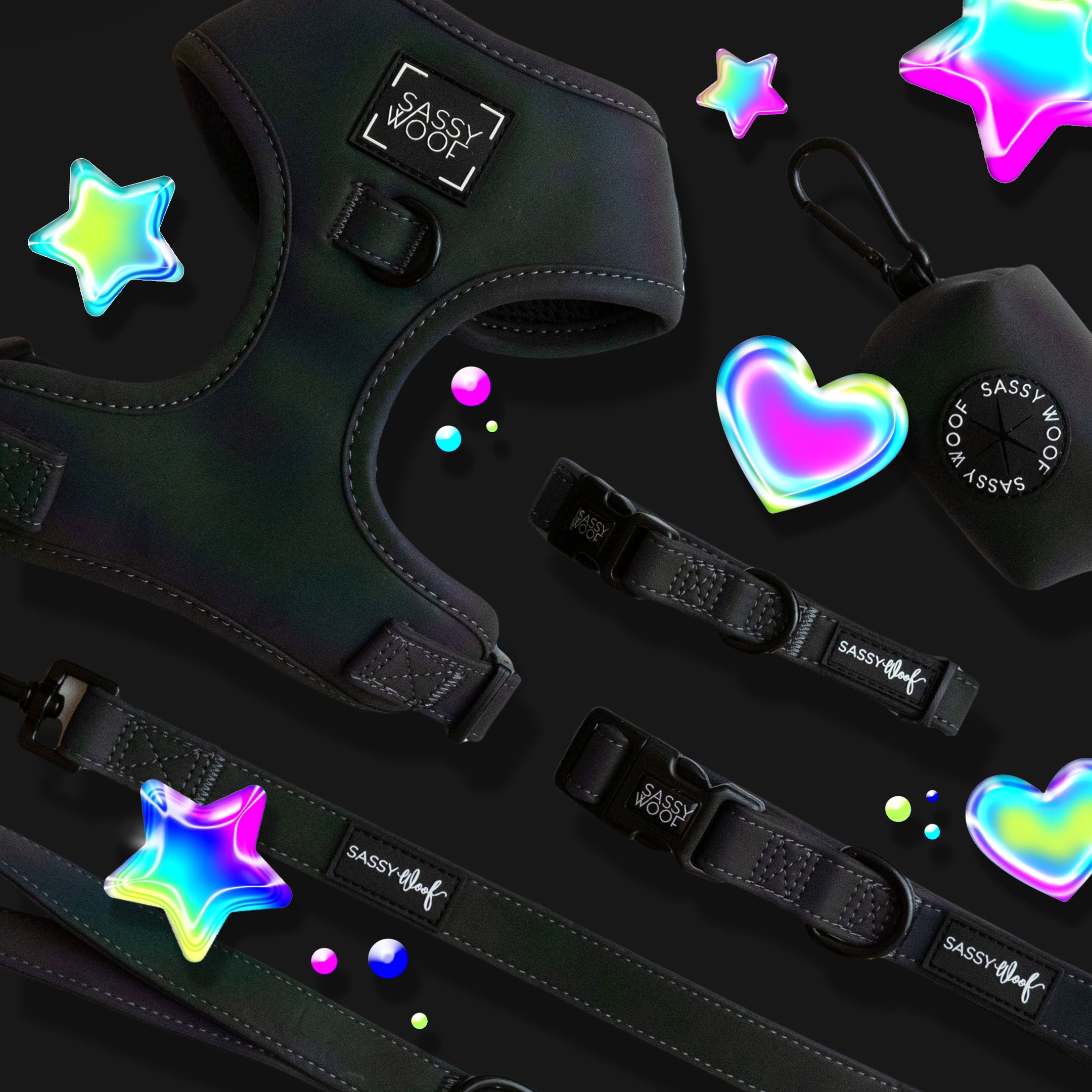 Black Sassy Woof dog harness, leash, collar, and waste bag holder are arranged on a black background with colorful, iridescent stars, hearts, and bubbles scattered around.