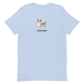 The Aussie Mom Tee by Sassy Woof is a light blue, eco-friendly cotton unisex shirt featuring a centered Australian Shepherd illustration and bold black lettering—a perfect pick for proud dog lovers.