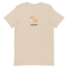 The Sassy Woof Corgi Mom Tee is a beige shirt with a cute corgi illustration and "Corgi Mom" text—perfect for corgi lovers.