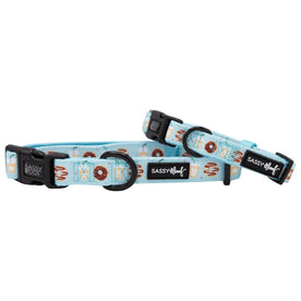 Two light blue Sassy Woof Dog Collar - Sweets & Pawfee collars with playful donut patterns and black plastic clasps. One is flat, one upright, both with metal rings for leash or harness attachment.