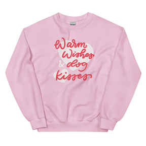 The Sassy Woof "Warm Wishes & Dog Kisses" sweatshirt features soft, light pink fabric with the phrase in playful red and white script across the front.